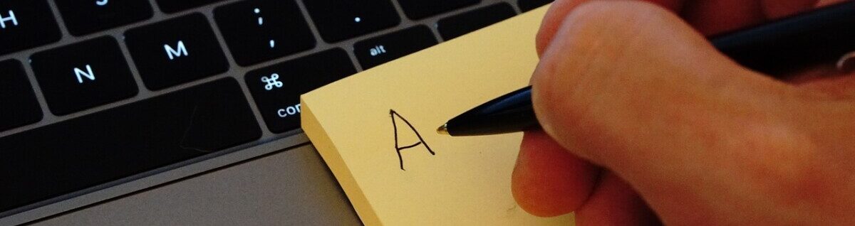 Gul post-it lapp med handskrivet A vid ett tangentbord.