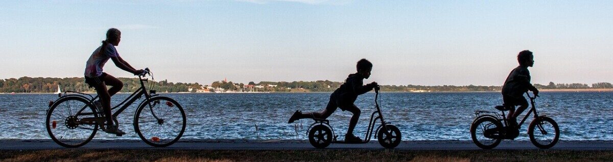 Tre barn cyklar vid strandkant.